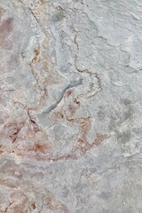 Natural stone texture with earthy tones of gray and rusty orange, showcasing rough surface patterns and organic details, ideal for backgrounds or design elements.