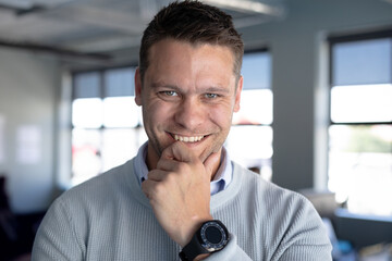 Confident businessman in office smiling while wearing smartwatch and casual sweater