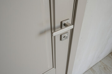 A close-up of a closed, gray door with a modern, rectangular silver handle and lock