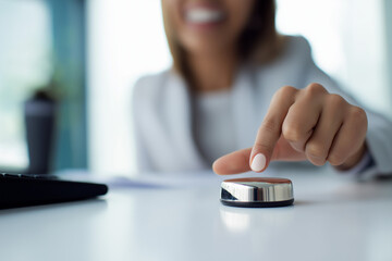 Close-up of smiling businesswoman&rsquo;s hand pressing buzzer button on office desk, concept of decision making and opportunity