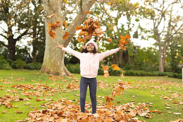 Joyful child playing with autumn leaves in park, smiling and enjoying nature