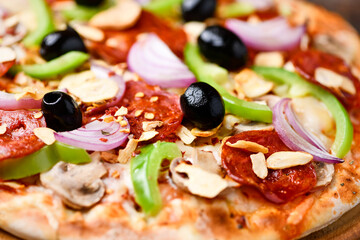 Pizza with chorizo ​​sausage, mozzarella cheese, green pepper and black olives. Rustic wooden background. Soft focus.	