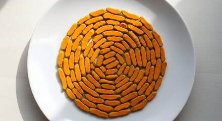 Vibrant turmeric root slices arranged in a beautiful spiral pattern on a white plate