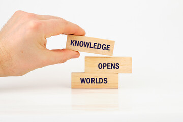 Academic education learning concept. Words KNOWLEDGE OPENS WORLDS made from blocks with hand on white background
