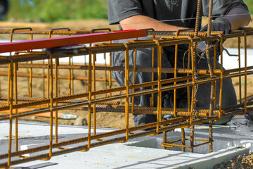 
Close-up of worker's hands in gloves, who is tying reinforcement for foundation reinforcement.
