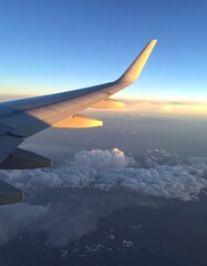 Obraz premium Airplane wing over clouds at sunset