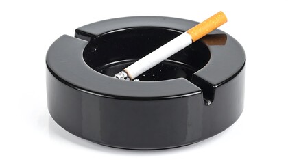 A glossy, round, black ceramic ashtray holds a discarded cigarette.