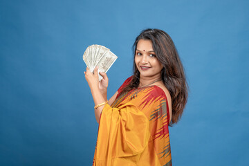 Happy Indian woman in saree holding money and showing thumbs up gesture