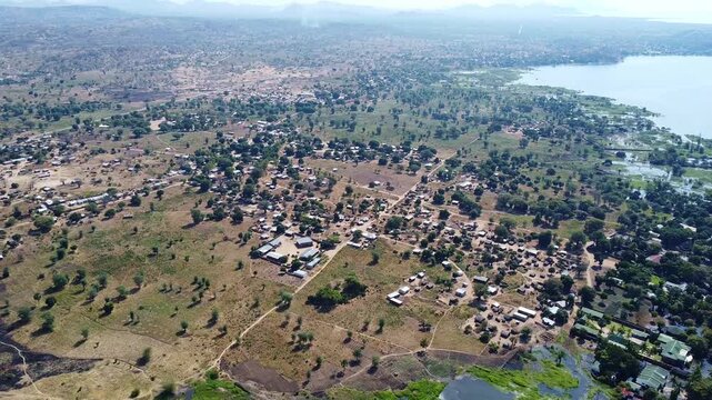 Aerial view of a rural african village with scattered houses, trees, and vegetation near lake victoria
