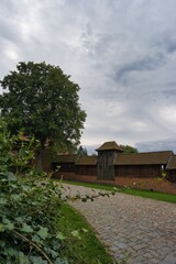 Old brick wall with a watchtower beside a winding path under a cloudy sky
