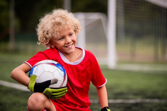 young boy football goalkeeper on artificial grass with ball.