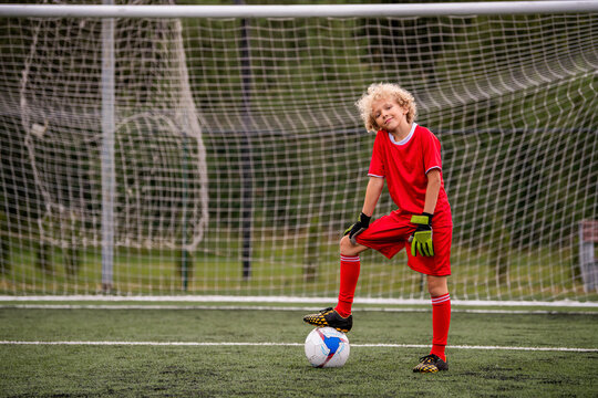 Boy football player with ball in his boot stands at the gate.