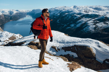 Hiker man in winter jacket looking distance on snowy mountain top