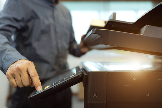 Office men use photocopy or copier machine at workplace is equipment for make a copy paper or photocopier for scanning document and photocopying service maintenance concepts.