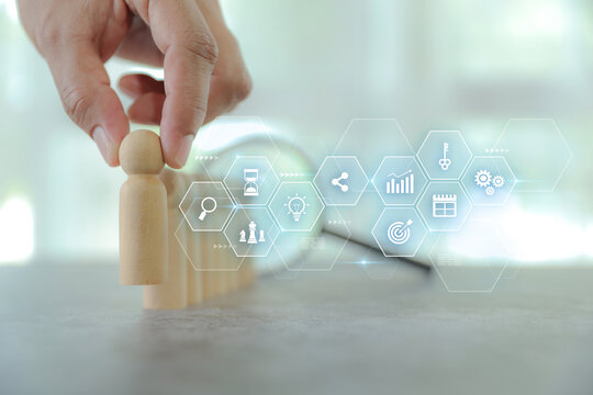 Hand chooses wooden person with HR human resources icons for personal leader training skill or leadership and challenge business team player and organization management teamwork.