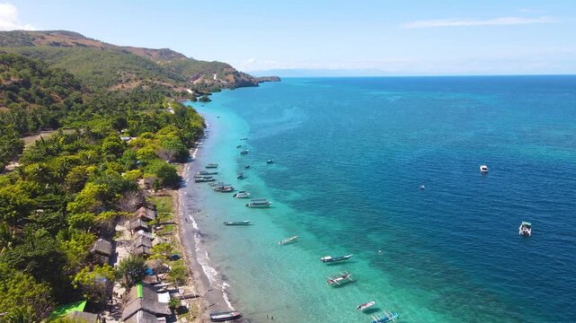 Stunning aerial view of the Atauro Island coastline in Timor-Leste. Traditional outrigger boats are moored in the clear turquoise water along an authentic fishing village.