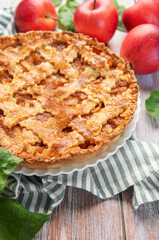 Freshly baked apple pie with red apples and leaves on rustic wooden table