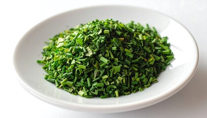 A vibrant pile of finely chopped chives sits on a white plate, showcasing a bright, fresh green hue.