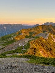 朝日に輝く蝶ヶ岳稜線と蝶槍へ向かう登山者