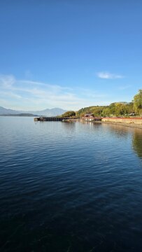 Bright view of Lago Ranco on a sunny day with blue skies, sparkling waters, and surrounding mountains, showcasing the natural beauty of southern Chile.