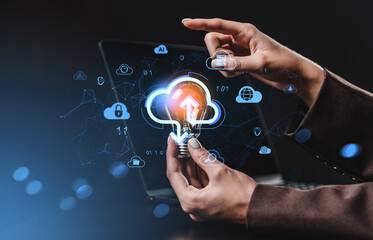 Hands holding lightbulb with cloud storage upload icon, digital data concept with online technology symbols glowing over dark laptop background.