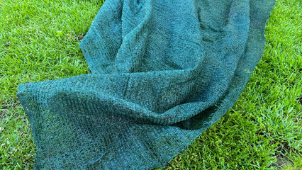 Woven verdant netting drapes gracefully over lush lawn, echoing tranquility of Earth Day and the...