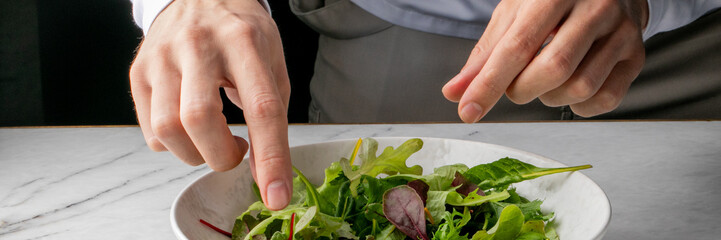 Chef's deft hands artfully arranging verdant salad, embody culinary zen, fresh beginnings, and spring equinox rejuvenation rituals