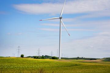 Fototapeta premium Wind turbine orchestrates natures symphony on rolling hills, echoing Earth Days sustainable dreams and Whispering Wind Festivals harmony