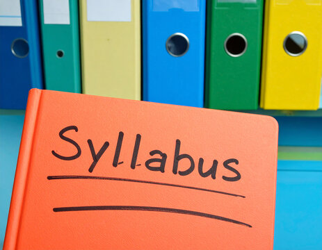 Orange book with syllabus written in black ink and colorful binders folders