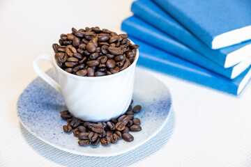 白いカップに山盛りにされた香ばしいコーヒー豆と、青い背表紙の本