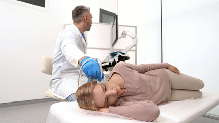 Obraz premium Sonographer examines brain of female patient by placing ultrasound transducer on temple of patient's head. Vascular ultrasound of migraine
