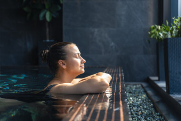 Woman relaxing in spa pool by the window. Quiet mindful pause.