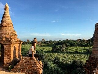 Solo female traveler, young Asian woman enjoys traveling in the ancient mysterious town of Bagan, Myanmar  - The magical town, Bagan with million of stupa and pagoda spreading across the green field 