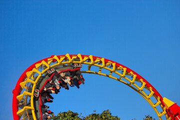 Riders experience an exhilarating upside-down inversion on a vibrant red and yellow roller coaster