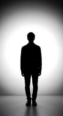 Obraz premium Full body silhouette of an anonymous man standing against a bright white and grey gradient background.