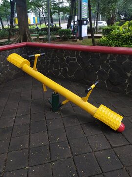 Playful Delight: A Vibrant Yellow See-Saw in a Tangerang Park Setting