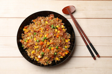 Tasty fried rice and chopsticks on light wooden table, top view