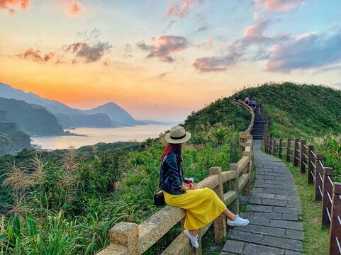 An Asian young solo female travel, a woman sits in front of the  panorama sea view, New Taipei City, Taiwan 