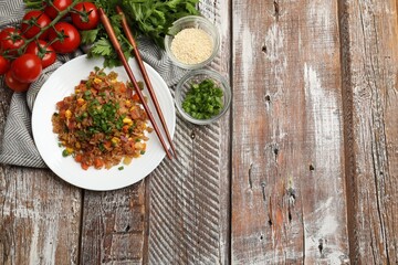 Delicious fried rice with vegetables and bacon served on wooden table, flat lay. Space for text