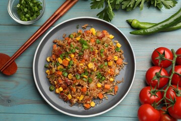 Delicious fried rice with vegetables and bacon served on light blue wooden table, flat lay