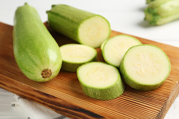 Fresh ripe zucchinis on white table, closeup. Whole and cut