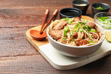 Tasty noodles with chicken, green peppers and sesame seeds served on wooden table