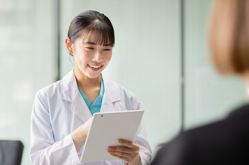 患者を問診する若い女性医師「撮影協力：スカパー東京メディアセンター」