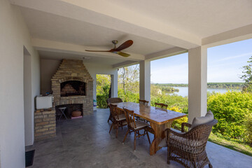 Covered patio with dining set, river view, and barbecue