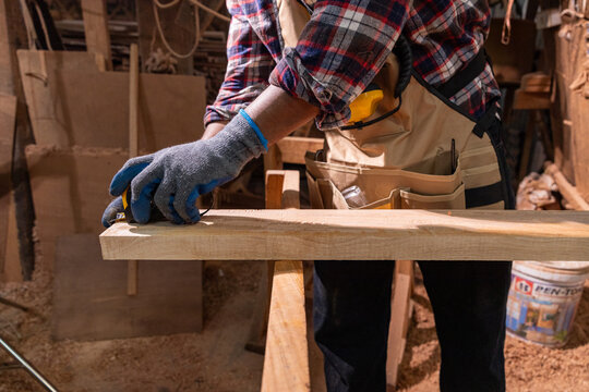 Focused carpenter measuring wood with tape