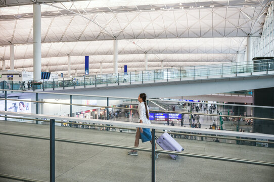 Asian woman at an airport walking with suitcase