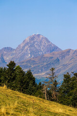 View of the Pic du Midi de Bigorre rising above the green valleys from the Col d’Aspin in the French Pyrenees, under a summer sky