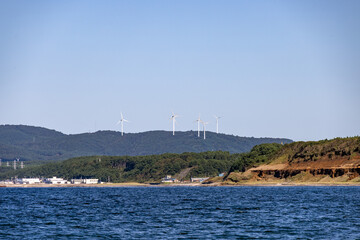海向こうの山々に立ち並ぶ白い風力発電用の風車