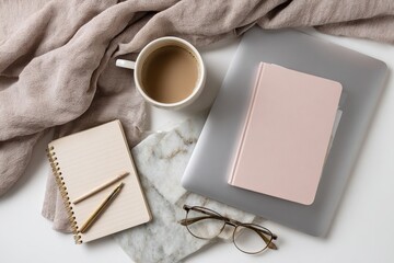 Workspace with coffee, notebook, laptop, and glasses on a white surface.