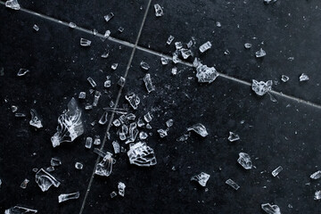 Shattered glass on black tiled floor with scattered fragments